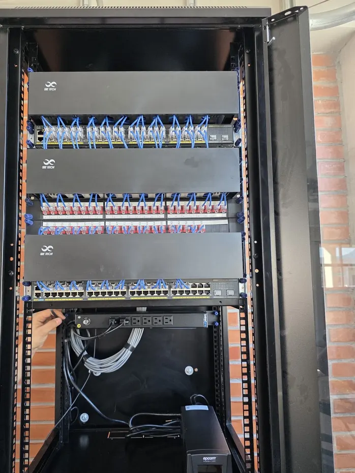 Rack de piso con organizadores de cable SB Tech, paneles de conectores rojos y patch cords azules